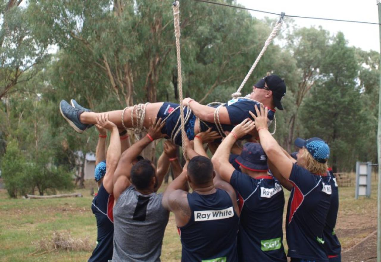 Team holding up tied and blindfolded person